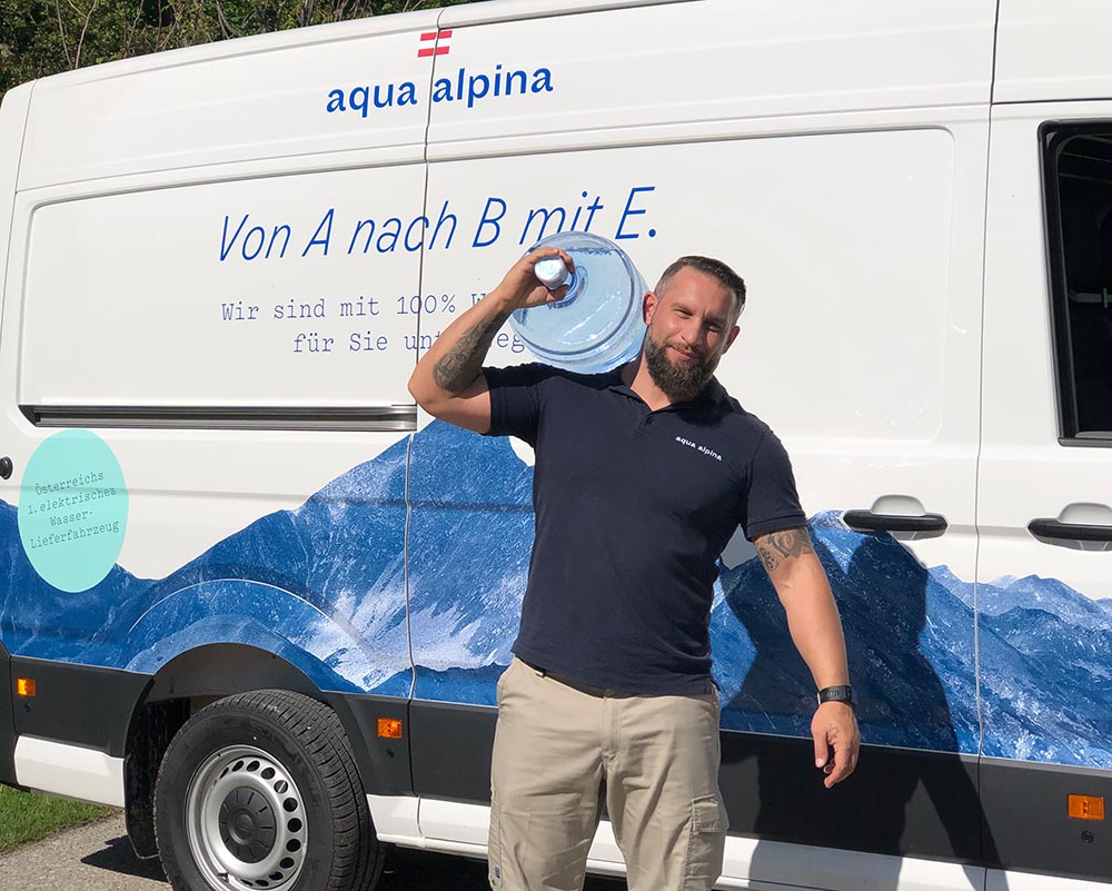 Servicefahrer mit Wasserflasche vor einem Elektroauto