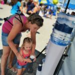 Familie trinkt vor Wasserspender