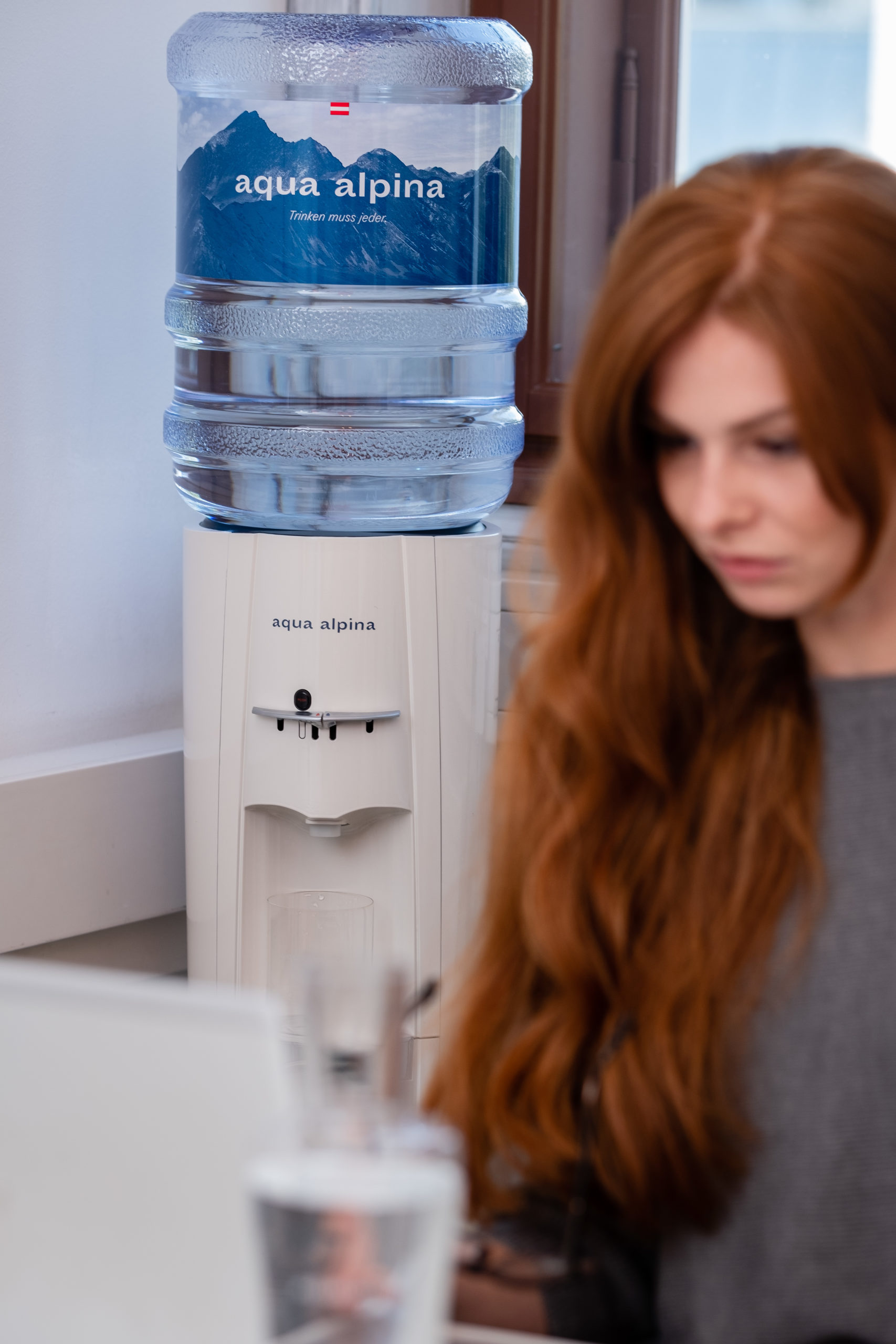 Frau Mit Roten Haaren Im Büro Mit Wasserspender Im Hintergrund